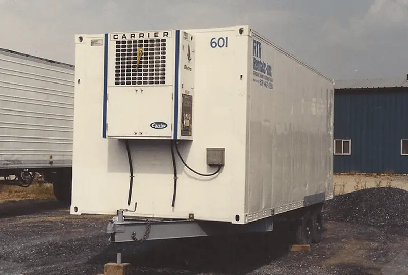 77image_desktop Refrigerated truck trailer parked on gravel.