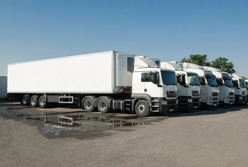 GettyImages-681070000 Row of white semi-trucks parked outdoors.