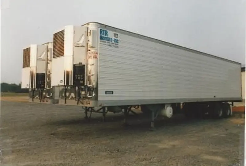 image_quad (1) Refrigerated truck trailers parked on gravel.